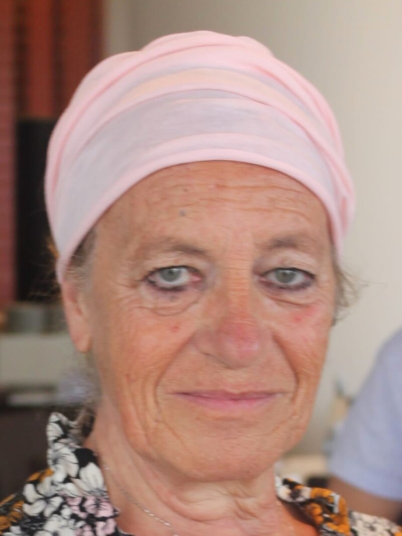 Ritratto di Ornella Levi. Indossa un turbante rosa pallido, una camicia a fiori e una collana con la stella di David.